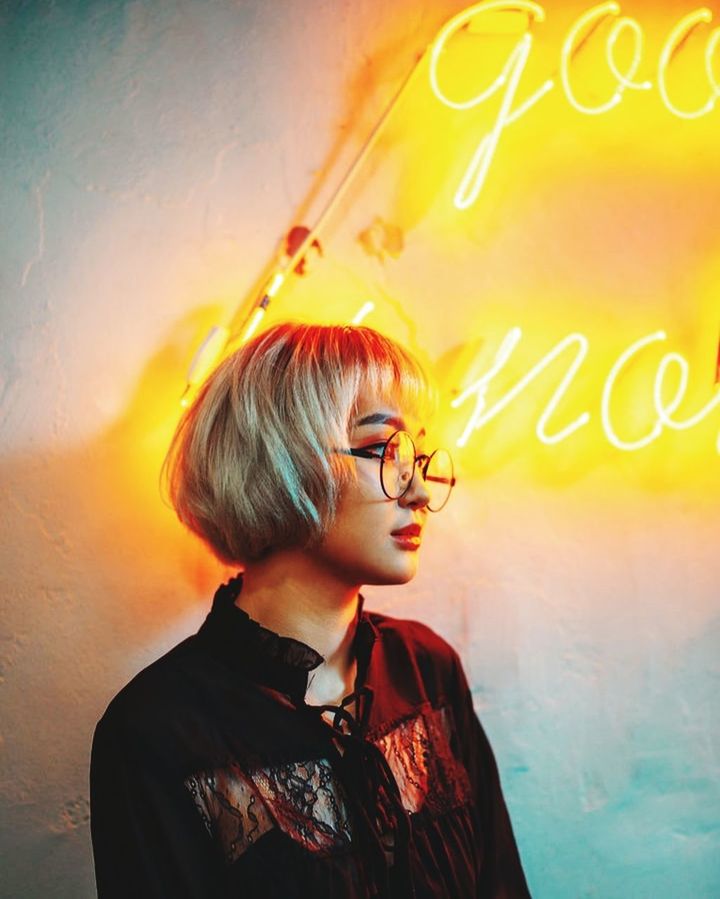 one person, glasses, fashion, adult, women, portrait, blond hair, young adult, eyeglasses, waist up, indoors, female, headshot, person, text, looking, poster, hairstyle, yellow, child, clothing, wall - building feature
