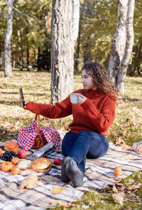 Leisure, free time. beautiful caucasian woman in red sweater on a picnic outdoors, sitting 