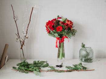 Flower arrangement in a vase on table against  white wall