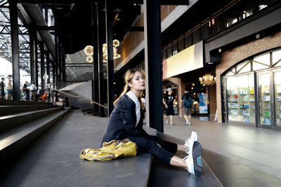 Portrait of man sitting on railroad station in city