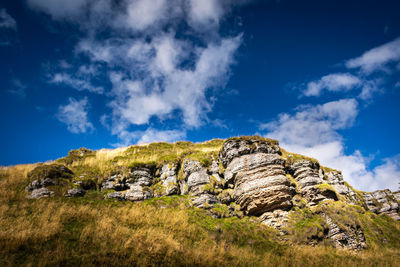 Low angle view of rocks against blue sky