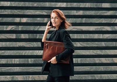 Portrait of young woman standing against wall