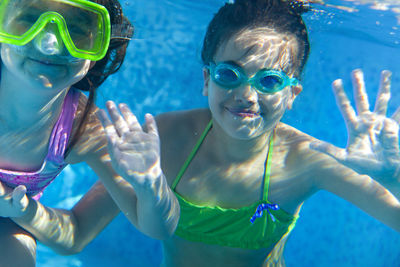 Portrait of sisters underwater in swimming pool