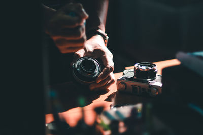 Midsection of person holding camera in darkroom