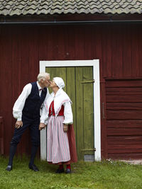 Senior couple wearing traditional costumes kissing in front of house, dalarna, sweden