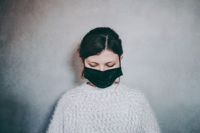 Portrait of young woman standing against white wall