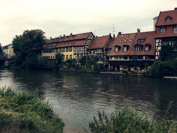 River by buildings against sky