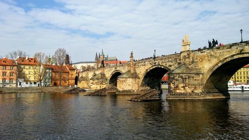 Arch bridge over river against cloudy sky