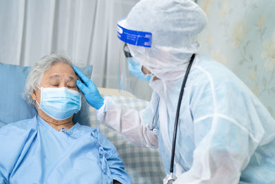 Doctor wearing protective suit examining patient at hospital