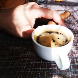Close-up of hand holding coffee cup on table