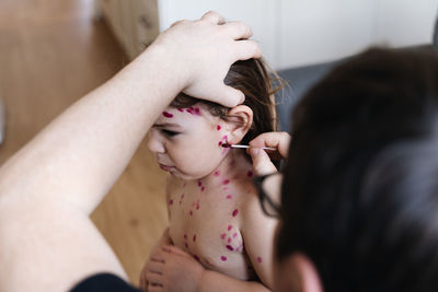 Man painting daughter at home