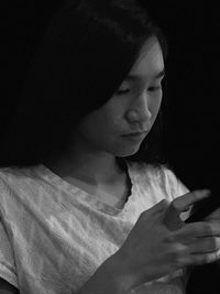 Girl using mobile phone against black background