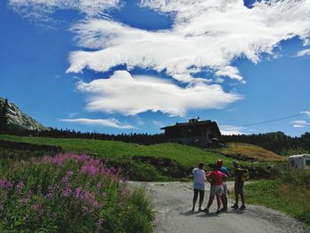 Rear view of people standing by flowers against sky