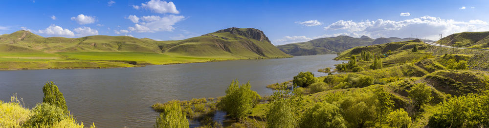 Panoramic view of green landscape and mountains against sky