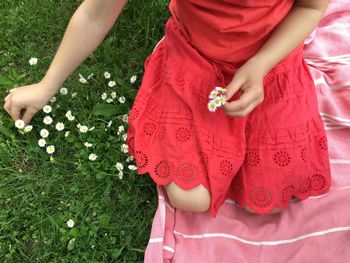 Midsection of woman holding red flowering plants