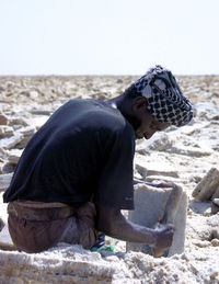 Side view of man sitting on beach