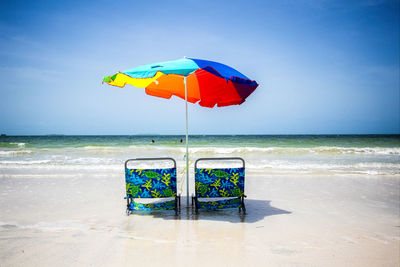 Multi colored umbrella on beach against sky