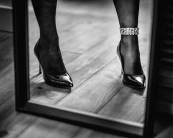 Low section of woman wearing high heels reflecting on mirror