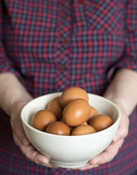 Close-up of woman holding bowl with eggs