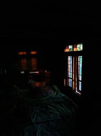 Illuminated electric lamp on bed against house
