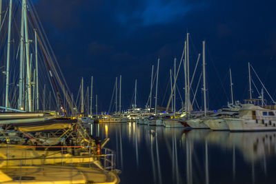 Boats moored at harbor against sky during night