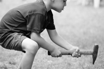 Side view of boy holding tool on land