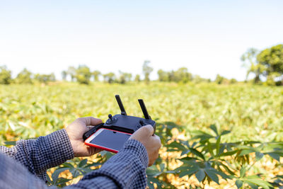 Midsection of person using mobile phone on field