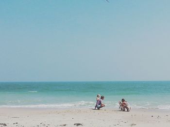 Children on beach against clear sky
