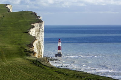 Lighthouse amidst sea and buildings against sky