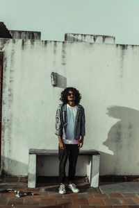 Portrait of young man standing against wall