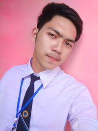 Portrait of young man standing against wall