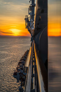 Railroad tracks by sea against sky during sunset