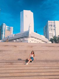 Woman on staircase of building against sky