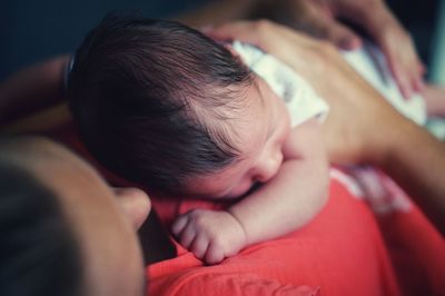 Close-up of woman with newborn son sleeping on bed