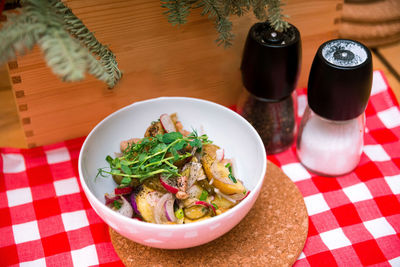 Potato salad in a deep bowl, microgreens. boiled potatoes, onion slices, pickled cucumber, radish.