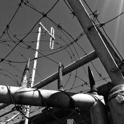 Low angle view of birds on cable against sky