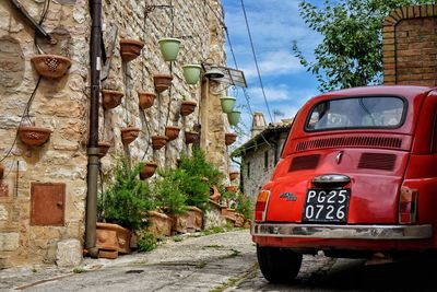 Red car on street by house against sky