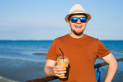 Portrait of young man wearing sunglasses against sea