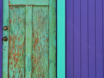 Weathered closed door on purple wall