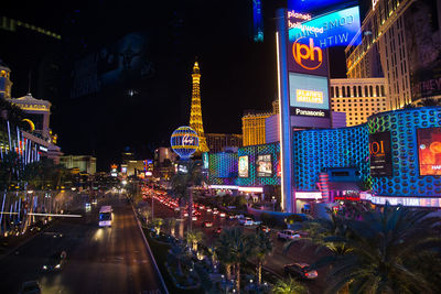 Illuminated street amidst buildings in city at night