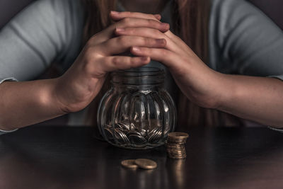Midsection of woman holding glass jar on table