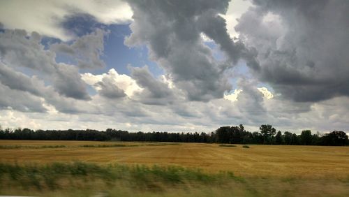 Scenic view of field against cloudy sky