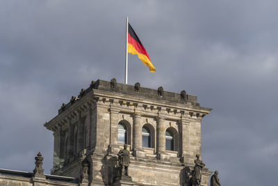 German flag fluttering against cloudy sky on the tower in berlin bundestag reichstag, parliament