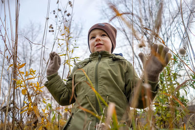 Low angle view of boy standing by plants