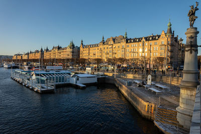 Sailboats moored on river against buildings in city