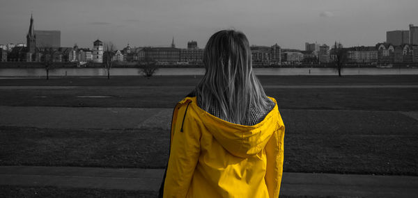 Rear view of woman standing against yellow city