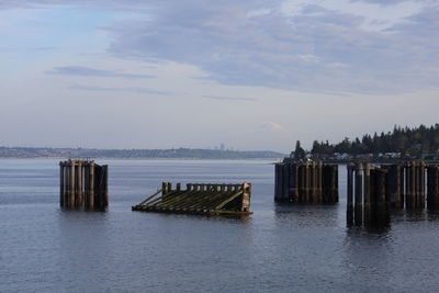 Wooden posts on pier over sea against sky