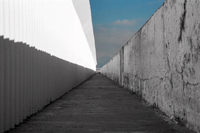 Walkway amidst buildings against sky