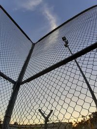 Low angle view of chainlink fence against sky