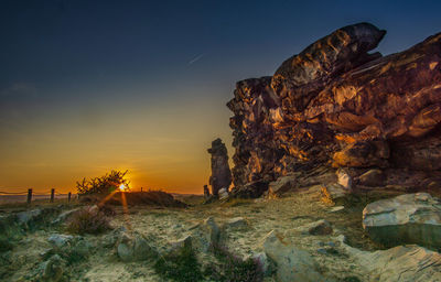 Rock formation on beach against sky during sunset